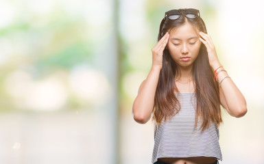 Young asian woman wearing sunglasses over isolated background with hand on head for pain in head because stress. Suffering migraine.