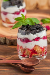 Trifle close up photography with fresh multi layered dessert with dairy and ripe raspberries and blackberries.