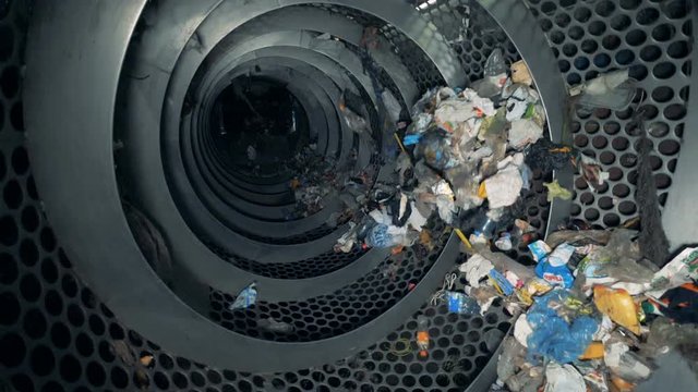 Recycling process at a plant. Rotating machine recycles trash in a waste center.