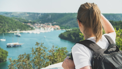 Obraz premium Female tourist with backpack looking at city near the lake.