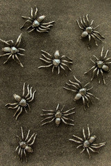 Black rubber spider toys on velvet background. Dark halloween october concept.