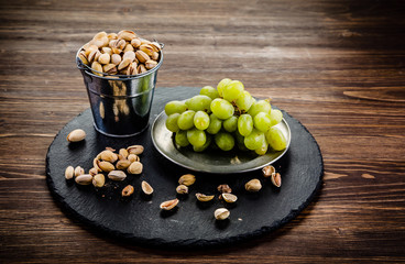 Pistachios and grapes on wooden table