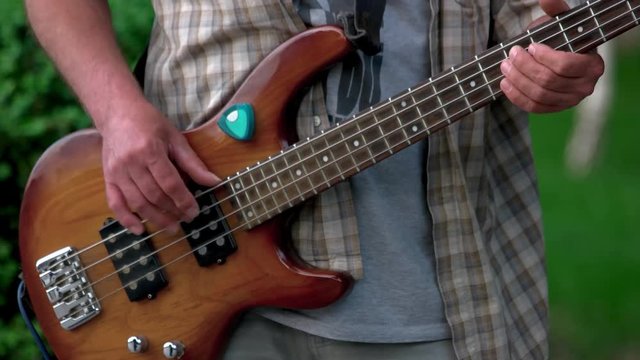 Man playing guitar outdoor. Polished wooden guitar, adult mature male hands.