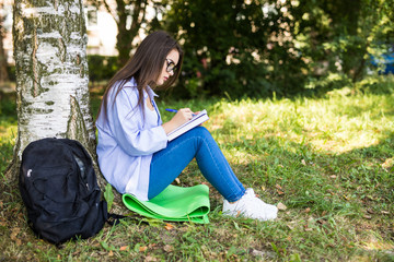 Naklejka na ściany i meble Student young woman doing homework in the park