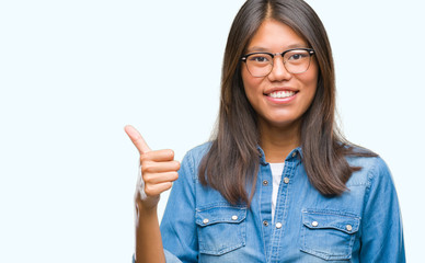 Young asian woman wearing glasses over isolated background doing happy thumbs up gesture with hand. Approving expression looking at the camera with showing success.