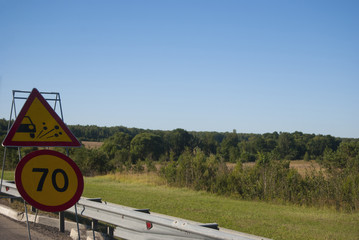 Two road signs: a speed limit of up to 70 and an ejection of gravel. Road repair.