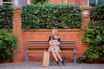 Young lady in dress sitting on bench with shopping bag on street of Bremen, Germany. Trevel...