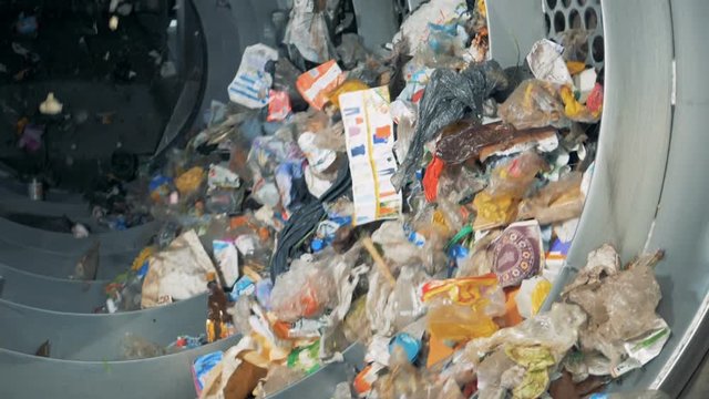 Rotating machine sorts garbage. Pile of garbage rotates at a factory for waste disposal.