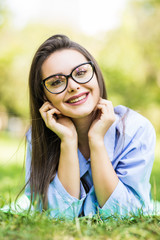 Beautiful smiling woman in glasses lying on a grass outdoor in the park