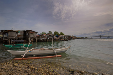 Fototapeta na wymiar small fisher boats in front a squatter area, stilt houses, twilight zone, slum area at the sea, , 