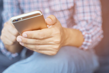 Young business man plaid shirt using on cell phone during rest in office. sitting sofa in watching message on mobile phone during break.