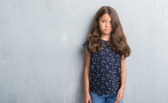 Young hispanic kid over grunge grey wall skeptic and nervous, frowning upset because of problem. Negative person.