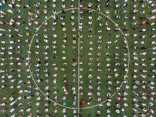 Top view drone of crowd of people on sports stadium football green lawn.