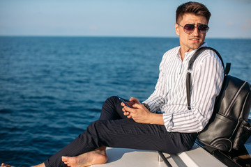 Cheerful european tourist with backpack on sailboat, relaxation in luxury sea boat trip, summertime leisure time on water transport, freedom and enjoyment concept