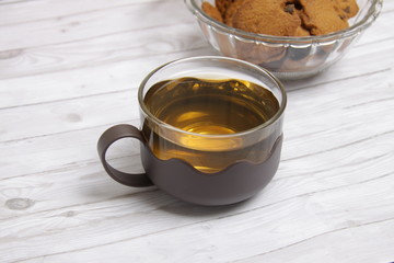cup of green tea on table and a bowl of choco chips cookies