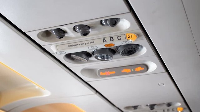 Closeup 4k video of emergency sign and fasten seat beat panel on the ceiling on passenger aircraft