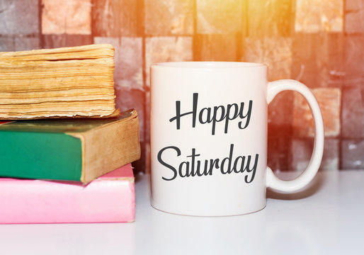 Happy saturday word on white morning coffee cup and books
