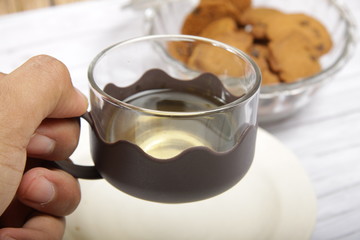 Men's hand holding a cup that contain green tea to drink