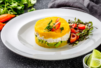 PERUVIAN FOOD. Causa rellena de pollo. Chicken causa rellena. Traditional peruvian dish from yellow potato, chicken, avocado on white plate