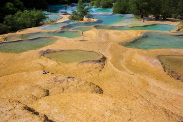 Pools of colorful blue water in Huanglong Scenic Area in Sichuan Province, China. Beautiful and exotic natural geological landforms caused by erosion over time, Yellow Dragon Chinese natural terraces