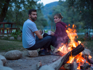 couple sitting around the campfire at evening