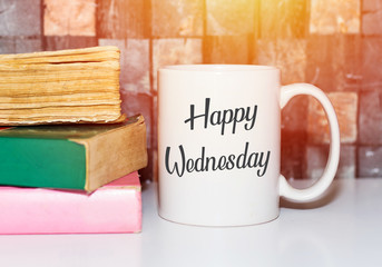 Happy wednesday word on white morning coffee cup and books