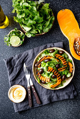 Grilled pumpkin and lettuce salad on dark background
