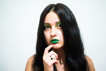Girl brunette with long hair on a white background with makeup green, lips painted with green sparkles