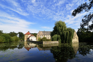 Fototapeta premium Wasserschloss Tatenhausen mit blauem Himmel und Wolken, NRW, Deutschland, Water castle Tatenhausen with blue sky and clouds, Germany