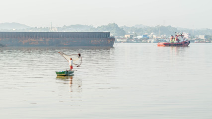 traditional fisherman in Mahakam river, Samarinda, Indonesia, catching fish using net in the morning