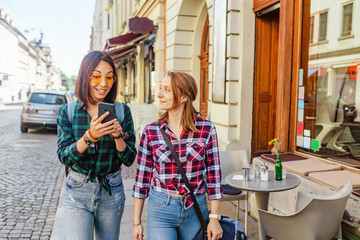 Couple of tourists walking at the old city street and looking to smartphone gps in search for...