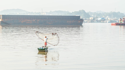 traditional fisherman in Mahakam river, Samarinda, Indonesia, catching fish using net in the morning