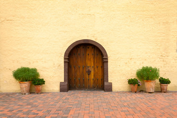 Fototapeta na wymiar Old California Mission Church Door with red brick floor and potted plants