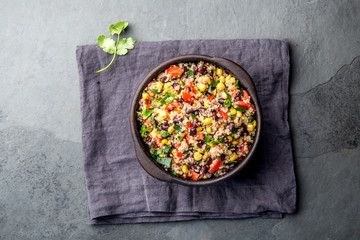 Mexican black bean corn quinoa salad in clay bowl top view, copy space