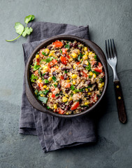 Mexican black bean corn quinoa salad in clay bowl top view, copy space