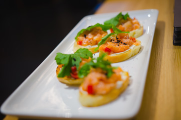Tasty Italian appetizers, or bruschetta, on slices of toasted baguette garnished with salmon basil.