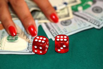 Woman playing scraps with dice cash on the green casino table