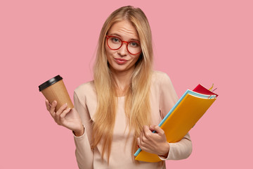 Pleasant looking clueless student with light straight hair, dressed in casual beige sweater, cant...