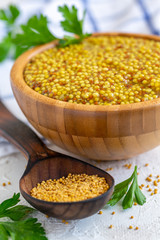 Grain mustard in a wooden bowl close-up.