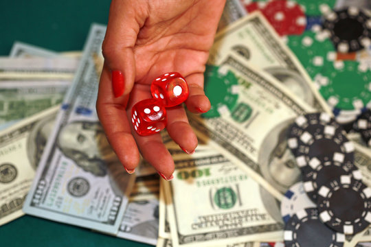 Dice in woman's hand with dollars and chips