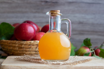 A bottle of apple cider vinegar with fresh apples