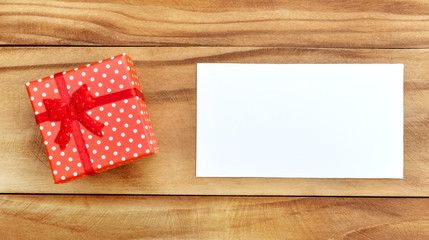 ed gift box with blank card on wooden background. Top view. Space for text.