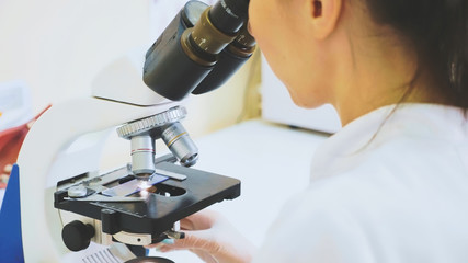 Veterinary worker using microscope for testing blood samples of animals