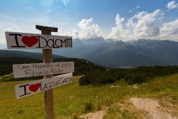 Italy. Dolomites. View from the mountain Paganella. On the left is a nameplate with the name of the area. Summer period.