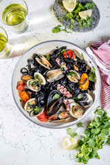 Homemade seafood Black pasta spaghetti with clams mussels octopus vongole in pan with white wine on marbled background