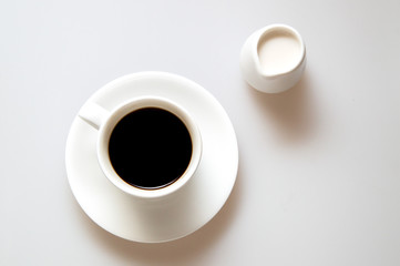 A cup of strong coffee and cream on white background. Top view, flat lay, close up.