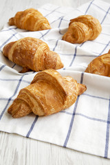 Fresh croissants on cloth on white wooden background, low angle view. Close-up. Selective focus.