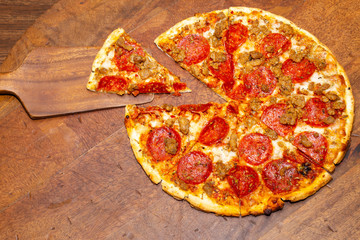 Pepperoni and sausage pizza cut in 8 slices with 1 slice removed demonstrating fractions for math classes. - obrazy, fototapety, plakaty