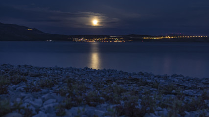 The moonlight in coastline landscape at evening. Dark stone beach and sea. 
