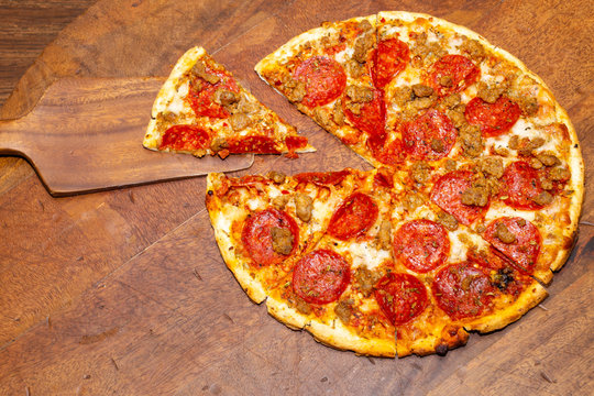 Pepperoni and sausage pizza cut in 8 slices with 1 slice removed demonstrating fractions for math classes.